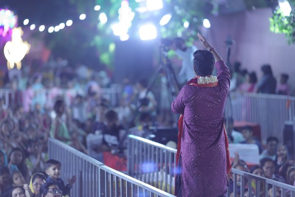 A singer of the party waving to a large crowd at an evening program