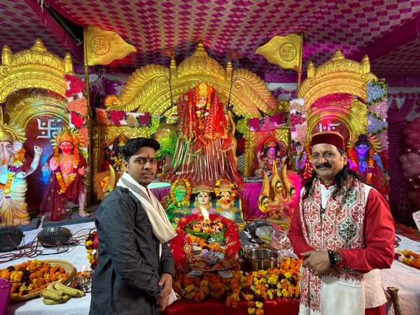Prem Bhatnagar ji and a young man standing before Mata's decorated darbar with the jyot lit