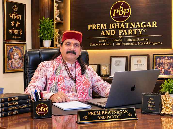 Prem Bhatnagar ji at his desk in the Prem Bhatnagar And Party office, with the PBP logo and the programs on the wall behind him