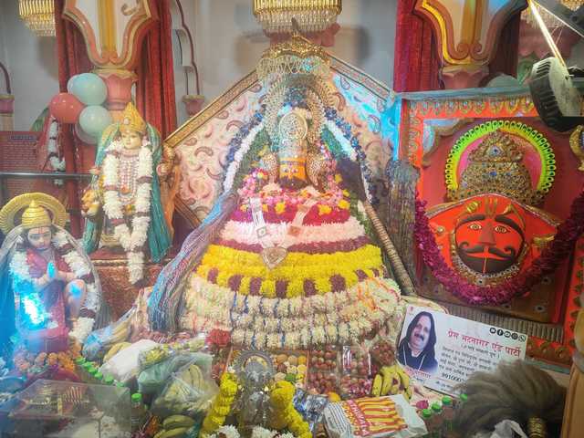 Shyam Baba's darbar dressed in tiers of flowers, with Hanuman ji, Mata Rani and Salasar Balaji ji beside him and bhog laid out in front