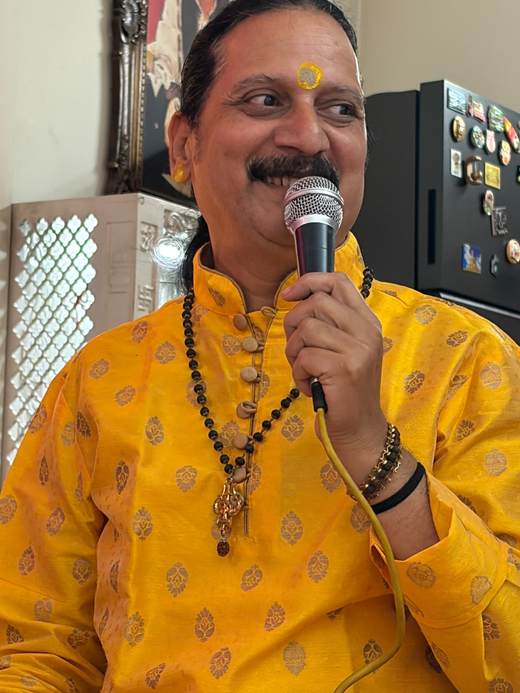 Prem Bhatnagar ji in a yellow kurta, smiling as he sings into the microphone
