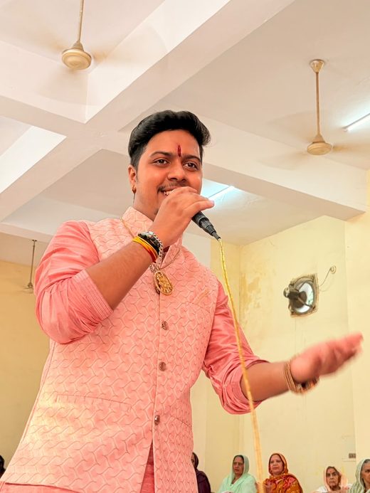 A singer of the party in a pink jacket singing to the gathering with an outstretched hand