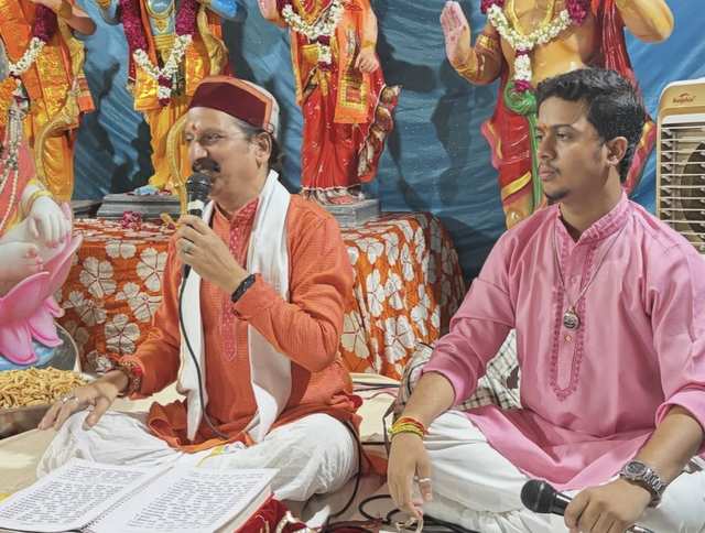 Prem Bhatnagar ji speaking during the katha, with a singer of the party beside him and Ram darbar idols behind
